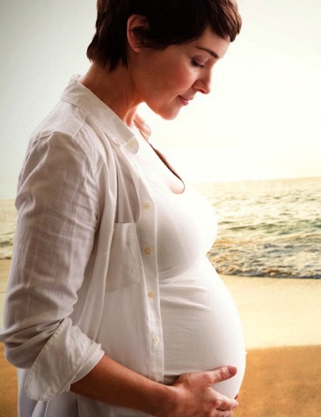 Pregnancy influences the expression in varicose veins causes here represented by mother gazing at her own pregnant belly while on a beach